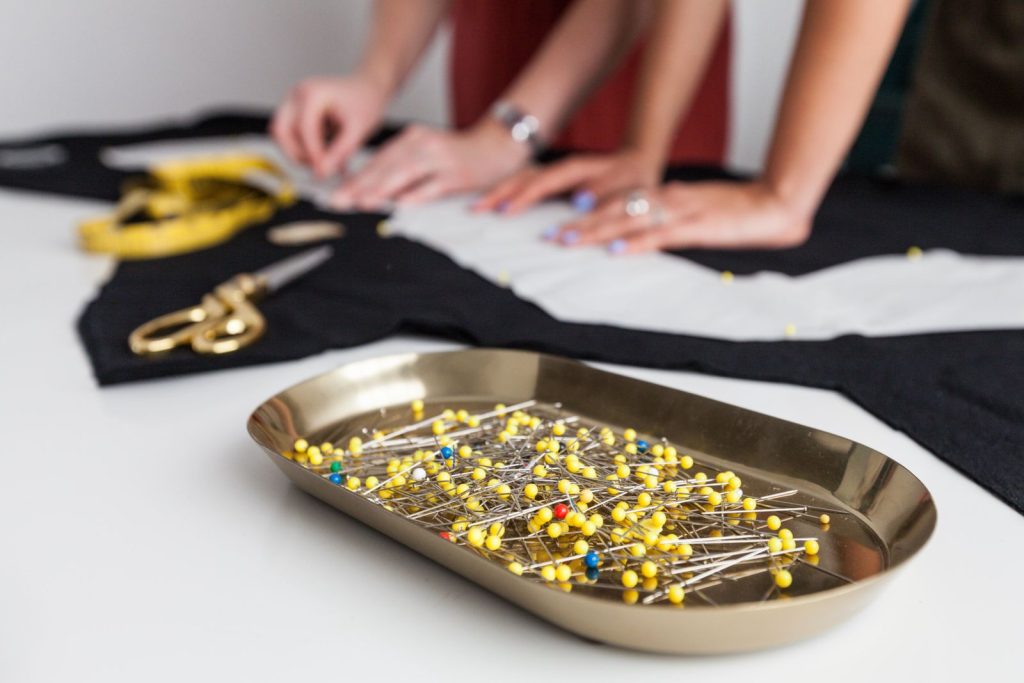 Scene d atelier de couture, artisans travaillant le tissu avec des epingles